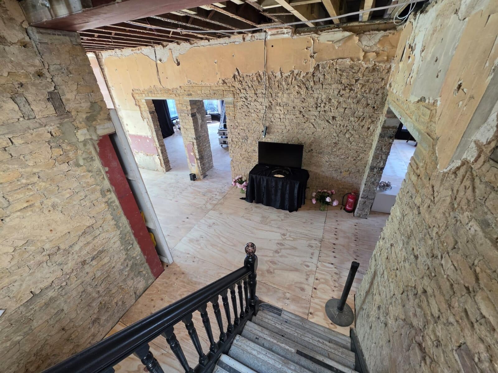 View down the original staircase into stripped-back rooms awaiting restoration