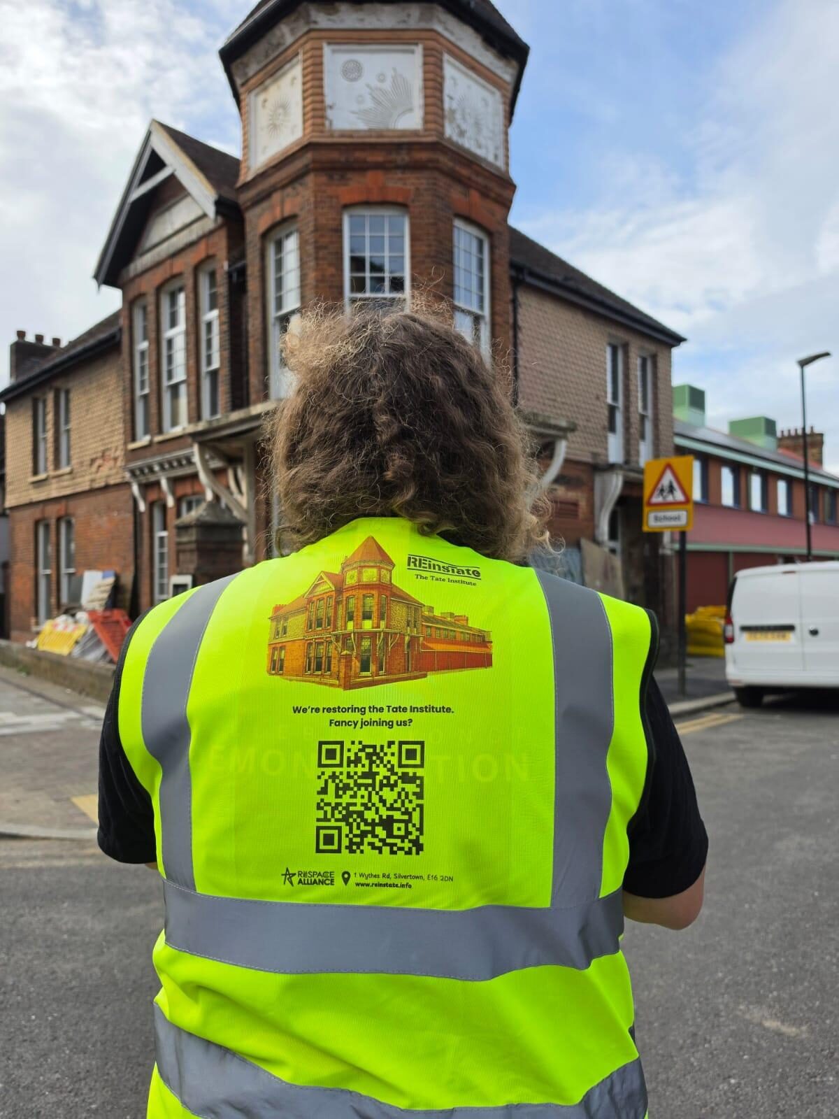 A volunteer in a REinsTate hi-vis jacket facing the Tate Institute: we're restoring the Tate Institute — fancy joining us?