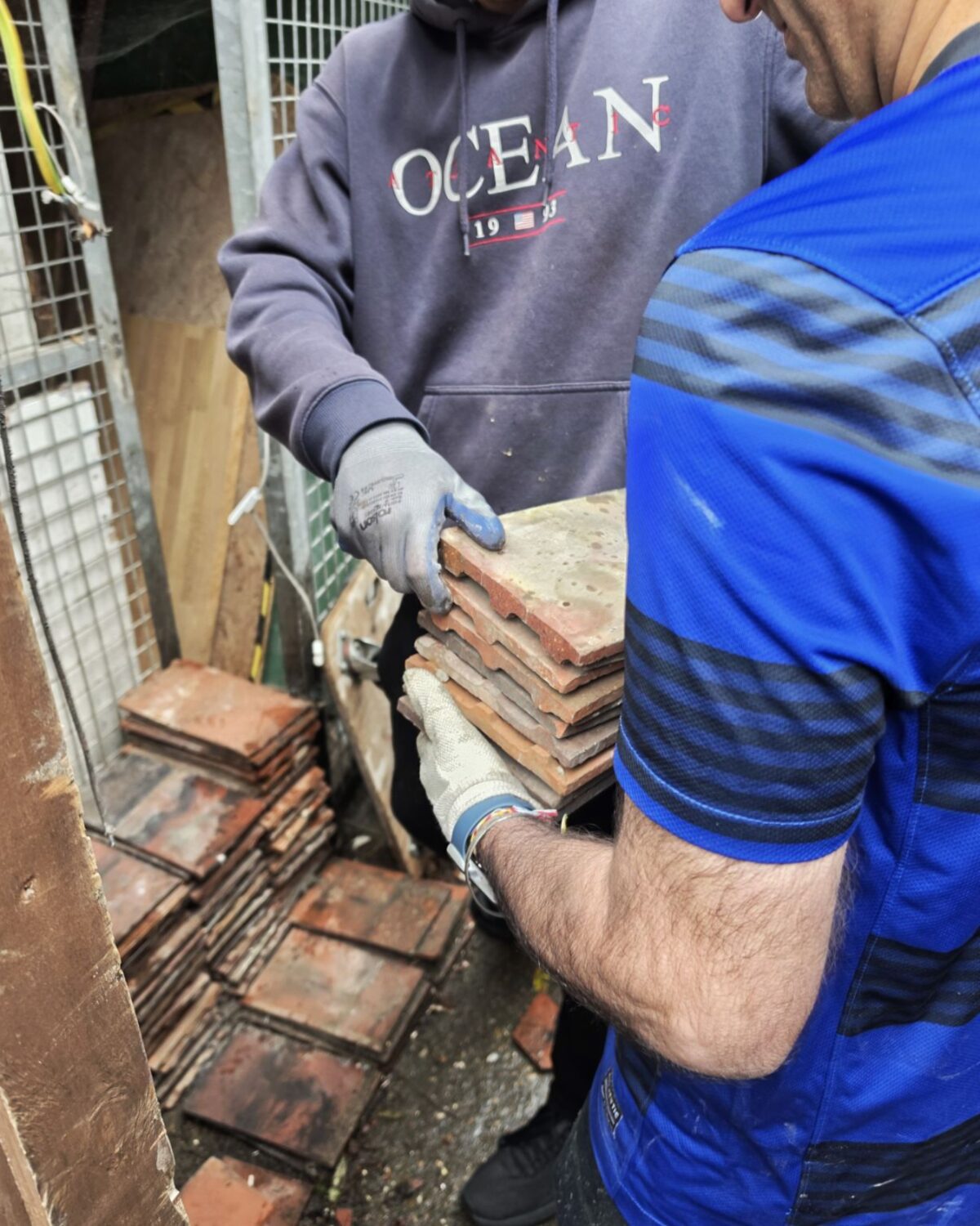 Volunteers passing stacks of reclaimed roof tiles for reuse